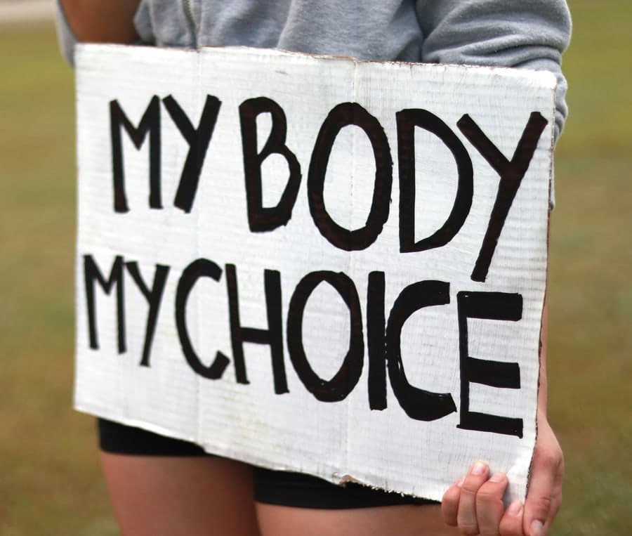 אישה מחזיקה שלט קרטון ועליו הכיתוב MY BODY MY CHOICE