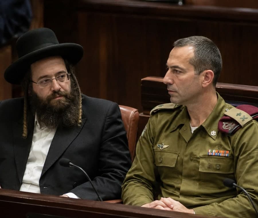 גבר חרדי יושב לצד קצין צה"ל במדים באולם מליאת הכנסת