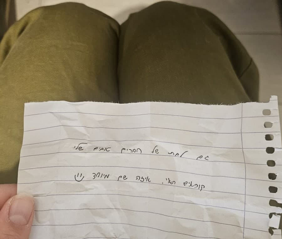 יד מחזיקה פתק כתוב בכתב יד מעל מדי צבא